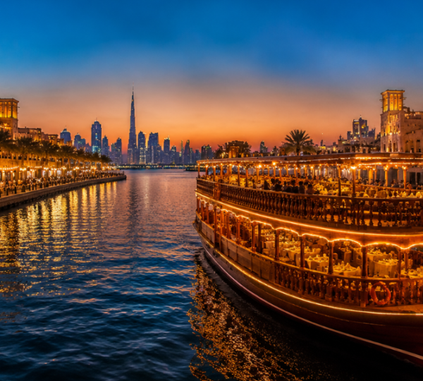 Dhow Cruise Al Seef Dubai – Traditional Waterfront Experience Traditional wooden dhow sailing along Dubai Creek at Al Seef with illuminated heritage buildings and waterfront views