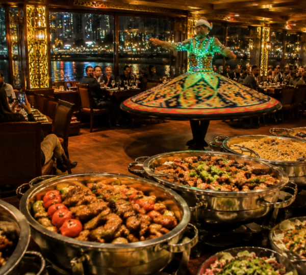 International buffet dinner spread and Tanoura dance performance on Dubai Water Canal dhow cruise with Business Bay skyline