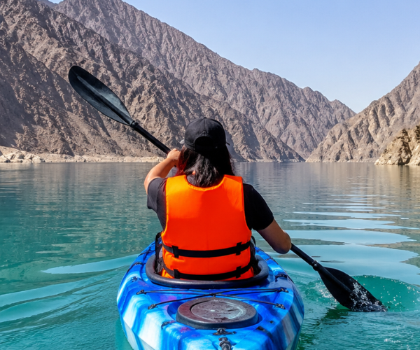 Al Rafisah Dam Kayaking โ Khor Fakkan Tour Person kayaking on calm turquoise Al Rafisah Dam with dramatic Hajar Mountains reflected in water
