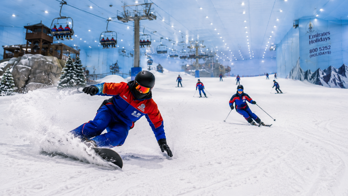 Skiing & Snowboarding at Ski Dubai – Slopes & Chairlift | Zutours Skiers and snowboarders descending the slopes at Ski Dubai with the chairlift carrying visitors up the mountain
